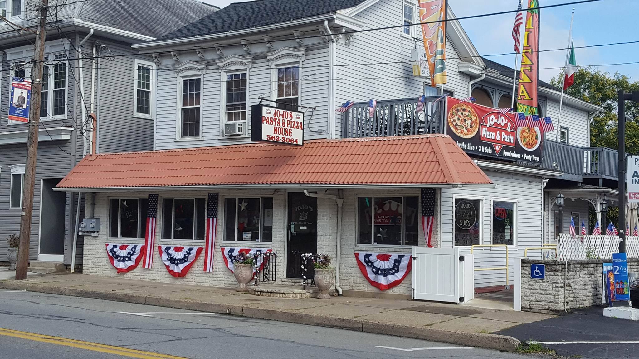 JoJo's Pasta & Pizza House storefront in Elizabethville, PA — decorated with American flag bunting, Italian flag, and the JO-JO'S PASTA & PIZZA HOUSE sign